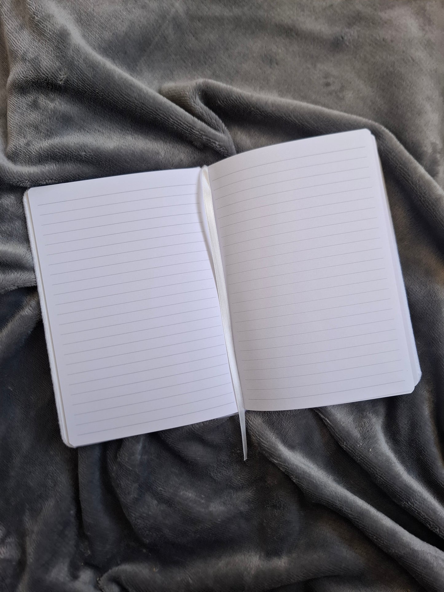 Open notebook with lined pages on a textured gray fabric background