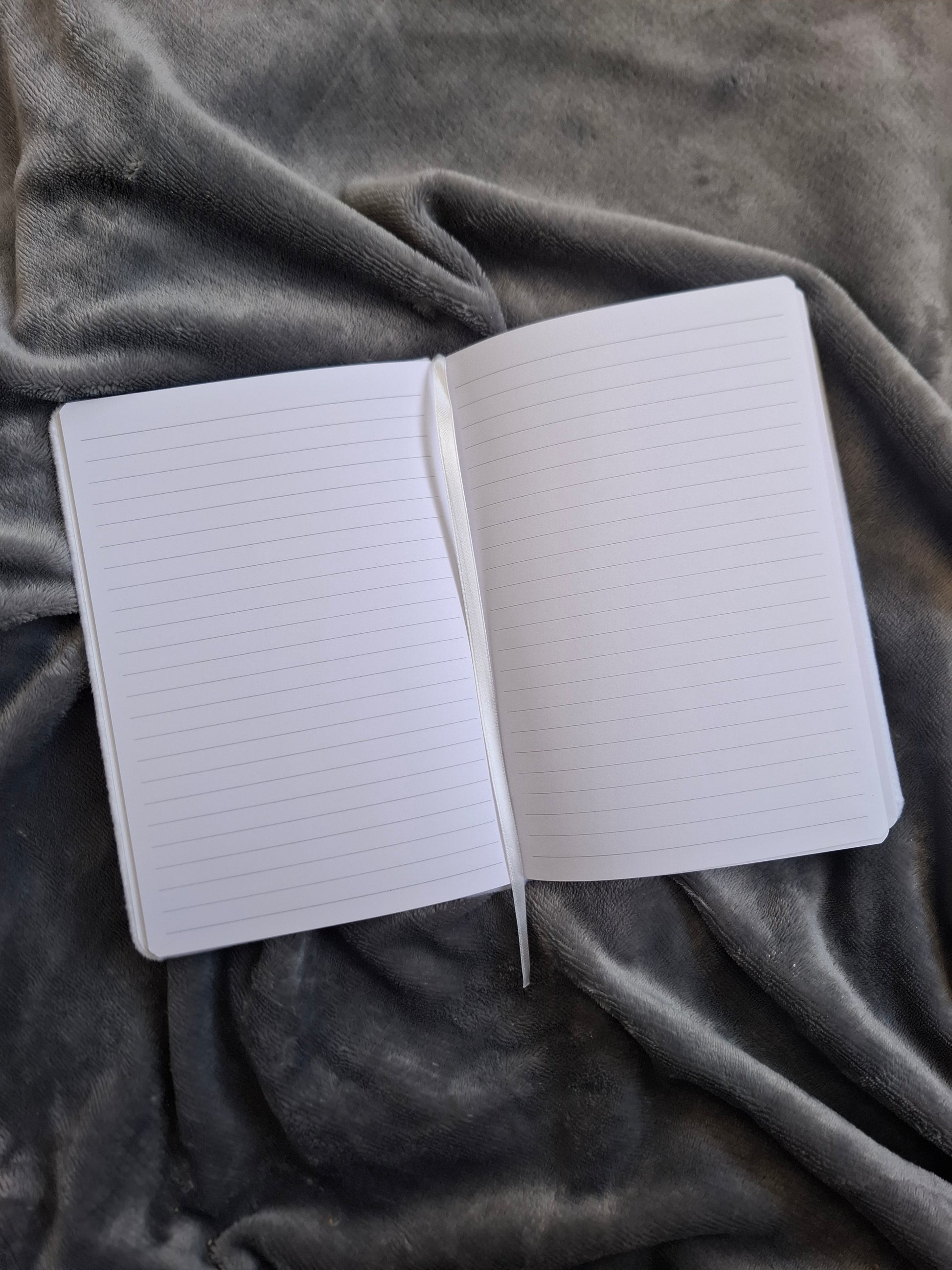 Open notebook with lined pages on a textured gray fabric background