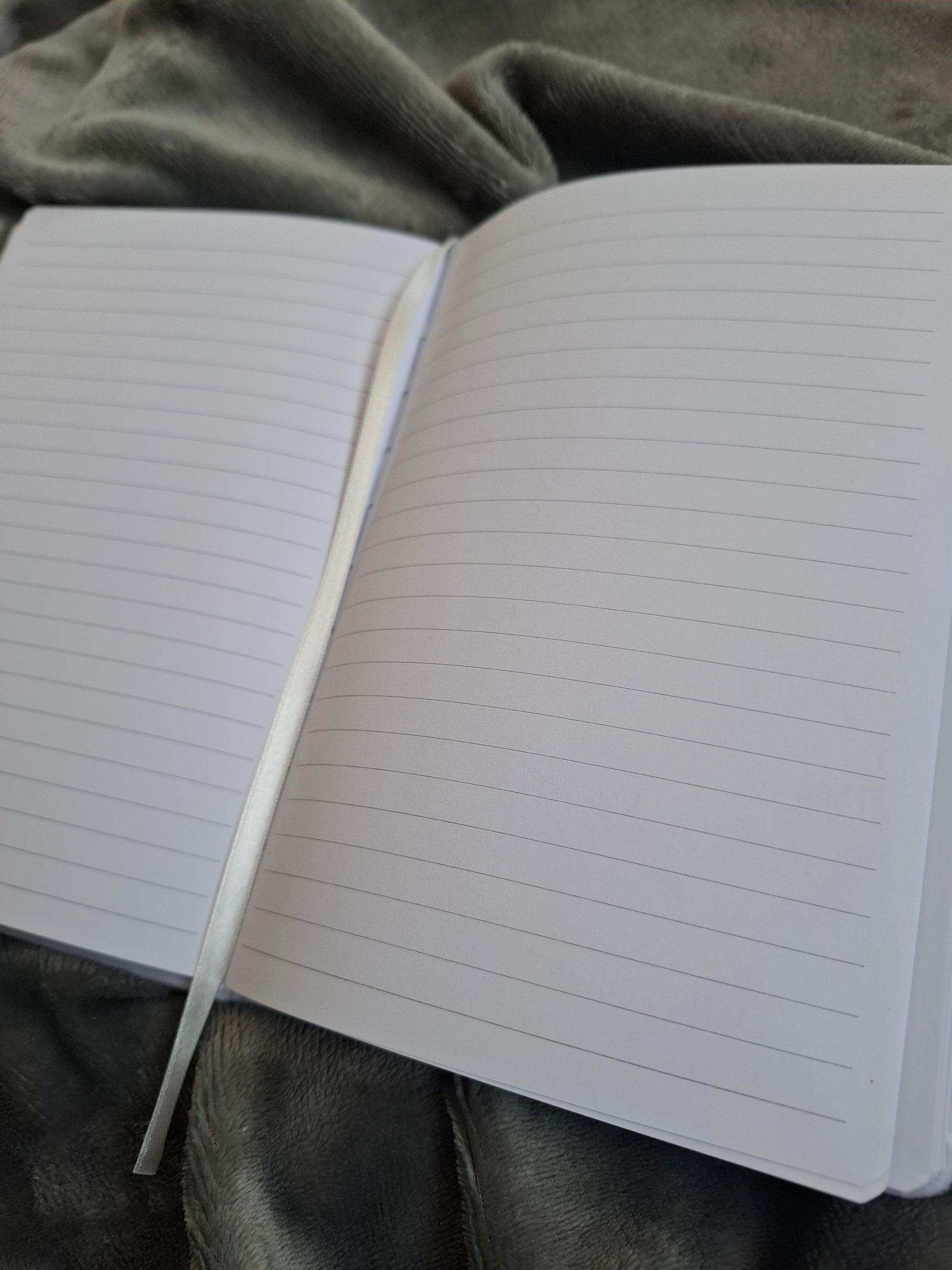 close up of the open notebook with lined pages on a textured grey fabric background