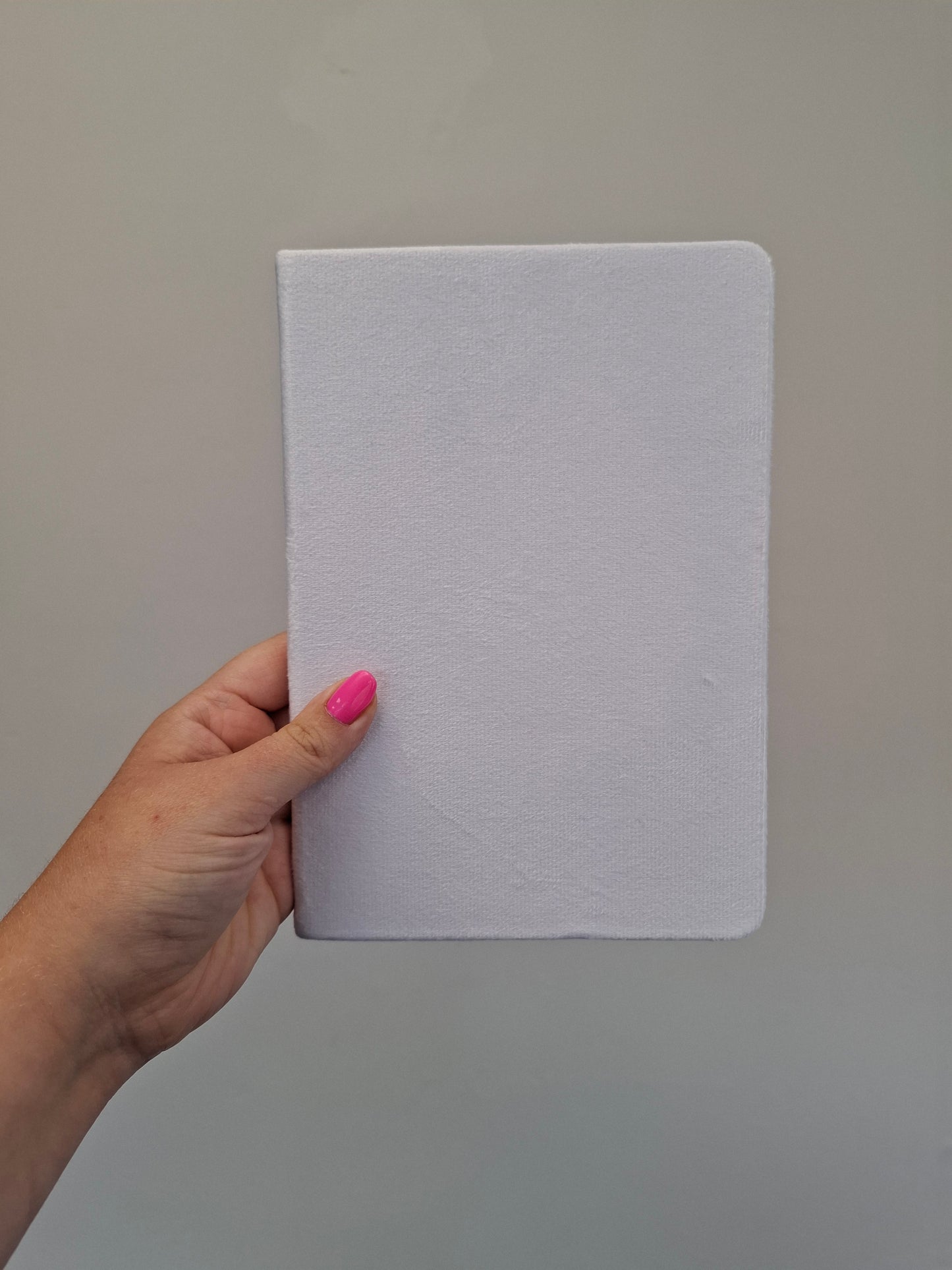 Hand holding a plain white A5 velvet hardback notebook 
