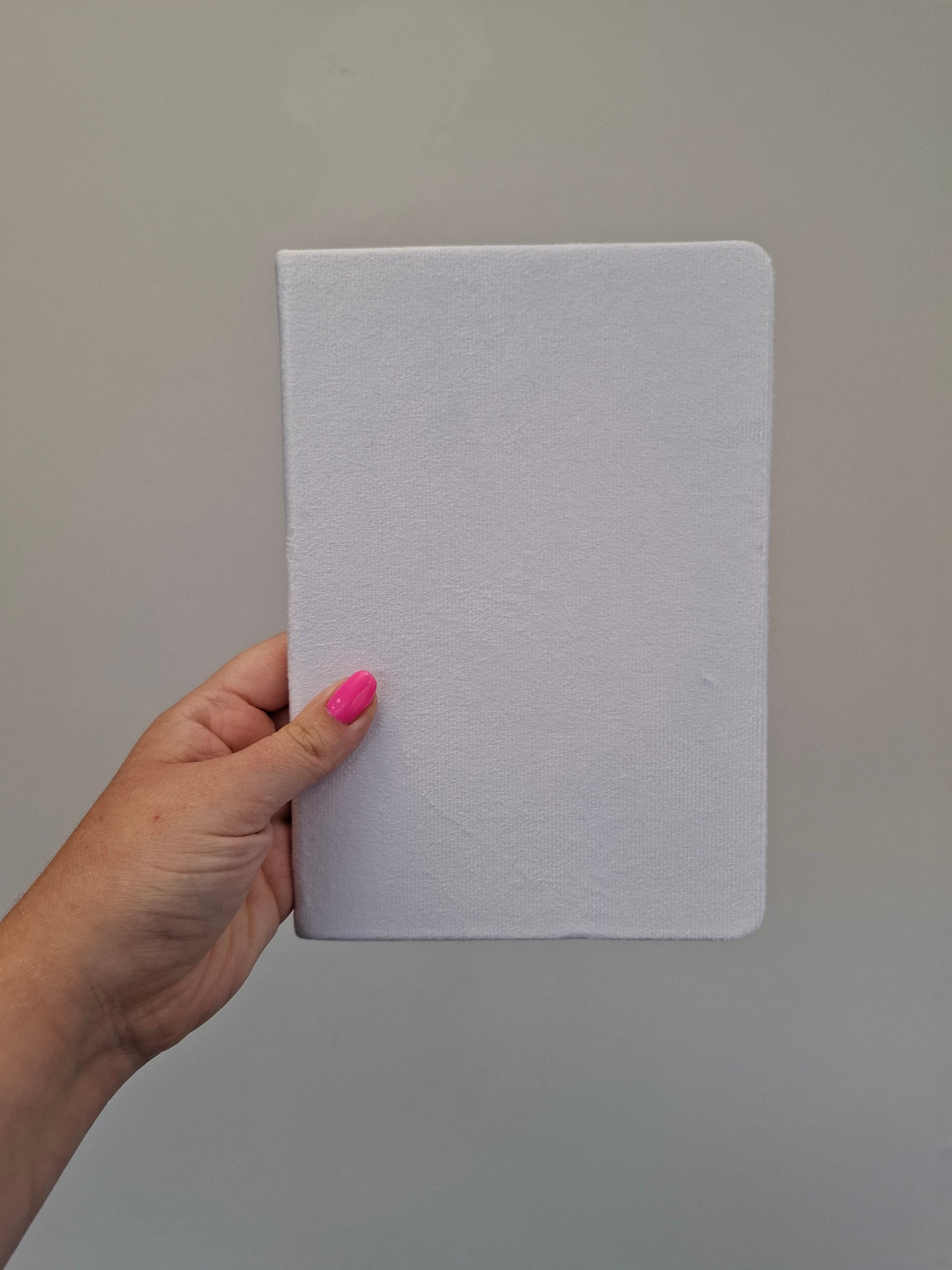 Hand holding a plain white A5 velvet hardback notebook 