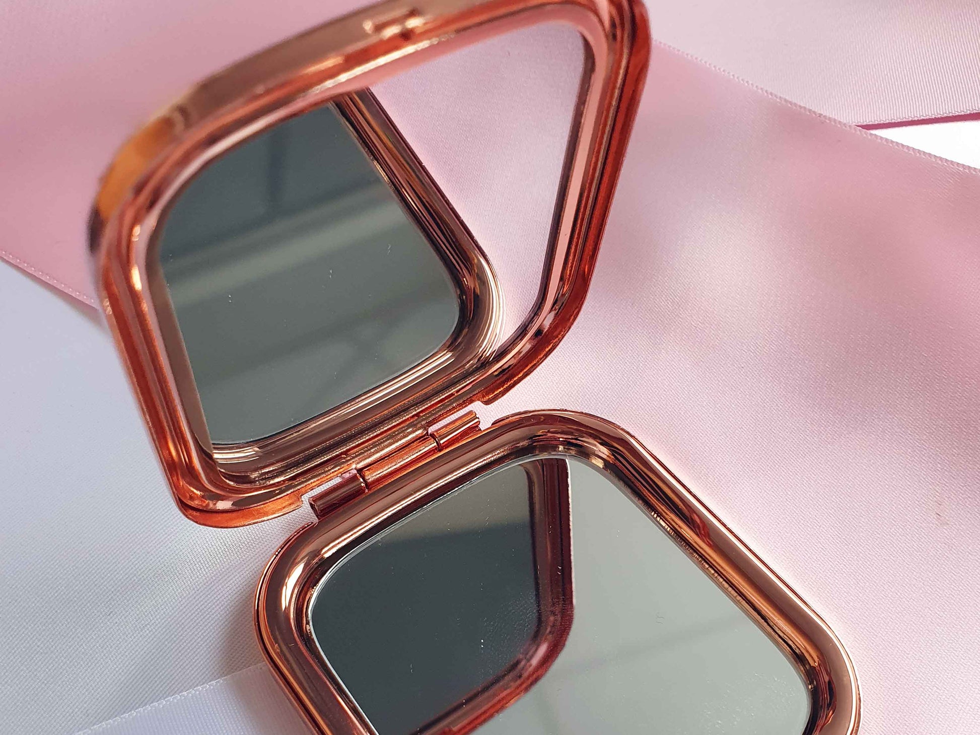 Image shows the pocket mirror open, with two mirrors inside facing each other.