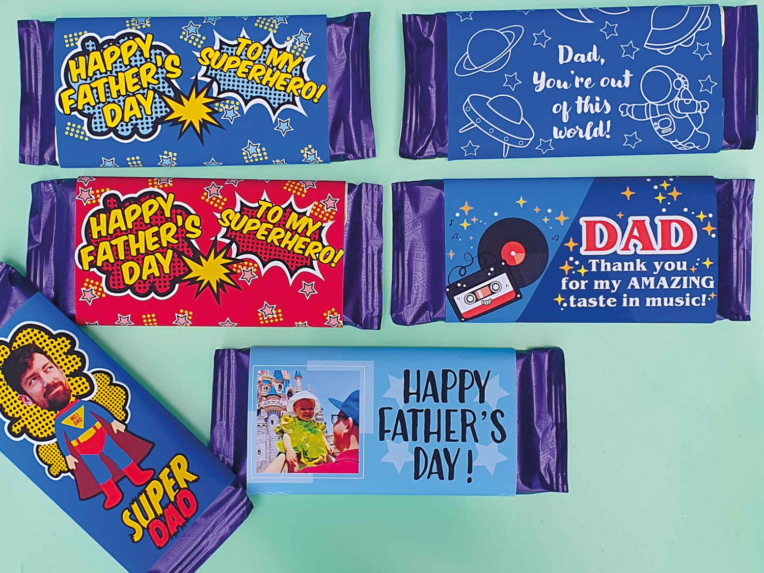 Personalised father's day chocolate bars a choice of six designs. Two say to my superhero one in blue the other in red. Another says 'dad you're out of this world' with a space design, another one says 'dad thank you for my amazing taste in music' with a vinyl record a cassette illustration,  another one says 'happy father's day' with a photo and another one says 'super dad' with a cartoon superhero and a photo of dads face as the head